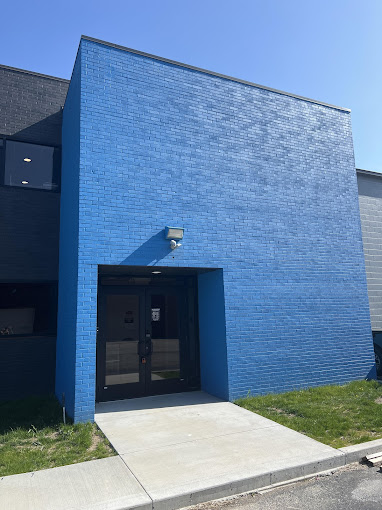 Blue building facade with a glass door entrance under clear sky.