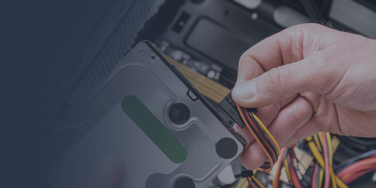 Hand connecting multicolored wires inside a computer.